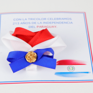 Escarapela tricolor con un dije dorado, con tarjeta tematica de festividades patrias